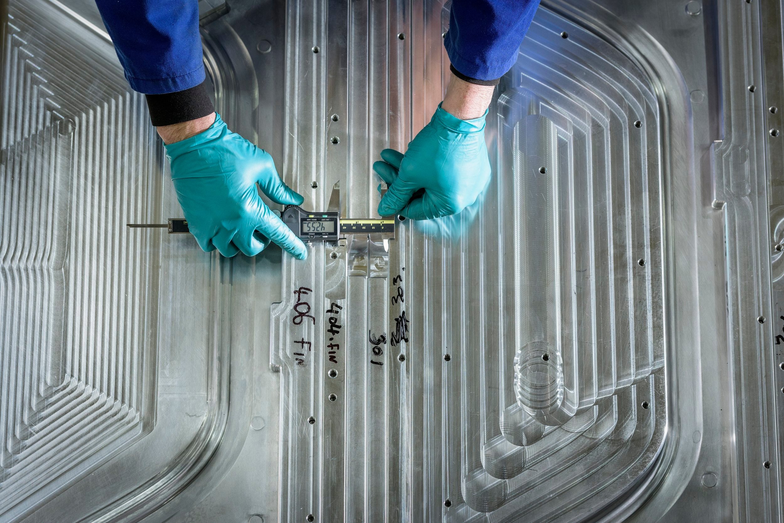 Gloved hands using a ruler on a piece of corrugated metal.